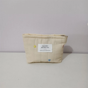Close-up of quilted makeup bag featuring colorful heart embroidery and secure metal zipper