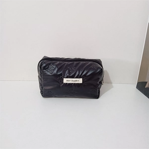 Close-up of black quilted makeup bag with butterfly embossing and May Rabbit woven label