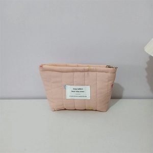 Detail of pink quilted fabric makeup bag with colorful heart embroidery and metal zipper