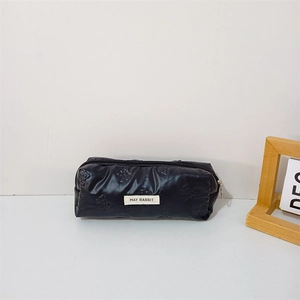 Detail of black puffy pencil case with butterfly embossing and May Rabbit woven label
