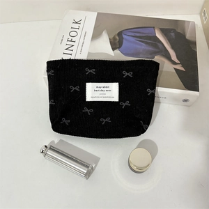 Gros plan détaillé d'une trousse à maquillage en velours côtelé noir avec motifs nœuds
