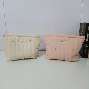 Detailed view of quilted cotton makeup bags with colorful heart embroidery and top zipper