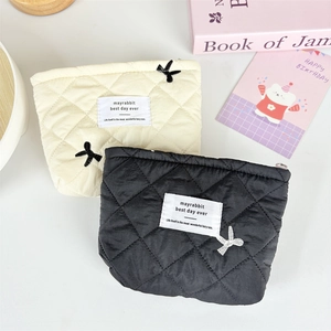 Detailed top view of quilted cosmetic bags with bow embroidery and diamond stitching