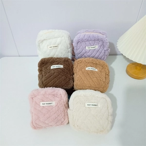Detailed view of square plush pouches in six colors with zippers and brand labels