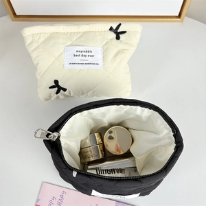 Close-up of quilted makeup bag with bow embroidery and smooth metal zipper details
