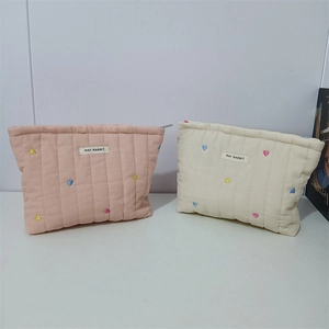 Close-up of quilted cosmetic bags with colorful heart embroidery and top zipper