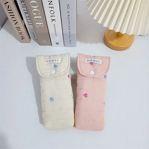 Detailed view of quilted cotton storage pouches with colorful embroidered heart patterns