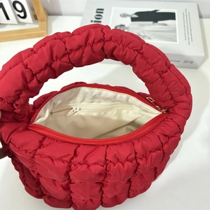 Top view of red quilted puffer bag featuring a secure zipper closure and white lining