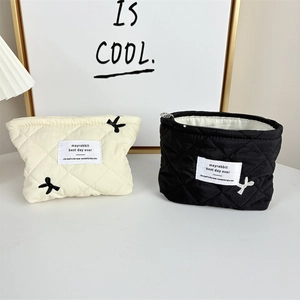Detail of embroidered bows and quilted diamond patterns on dual color cosmetic bags