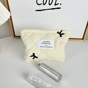 Detail of quilted cosmetic bag with cute rabbit embroidery and square woven label