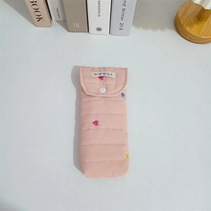 Detailed view of pink quilted fabric with colorful heart embroidery and white snap button