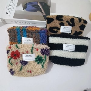 Detailed macro view of four plush teddy fleece cosmetic pouches with zipper and strap hooks