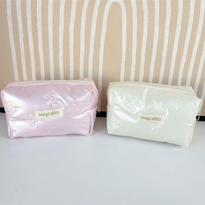 Close-up of quilted PU makeup bag with iridescent pearl finish and 3D bow pattern