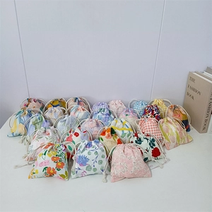 Close-up of floral and checkered cotton drawstring pouches with cream cords
