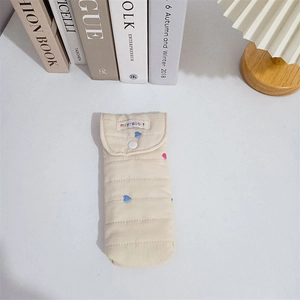 Detailed view of quilted fabric pouch with heart embroidery and snap closure
