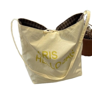 Cream canvas tote bag with yellow lettering and adjustable shoulder strap for travel