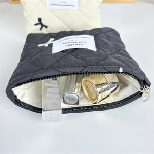 Detailed interior of black quilted cotton makeup bag showing silk lining and capacity