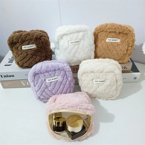 Detailed arrangement of soft plush cosmetic bags in various colors on decorative books