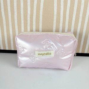 Detail of pink quilted makeup bag with bow patterns and metallic pearl finish