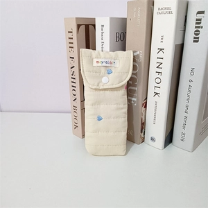 Close-up of quilted cream pouch with heart embroidery and snap button closure for glasses