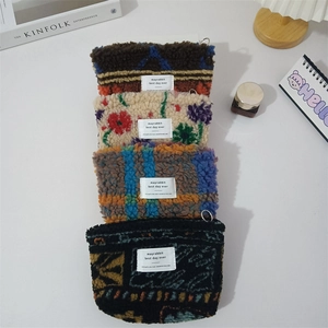Detailed view of plush lamb wool coin purses with floral and plaid patterns and metal rings
