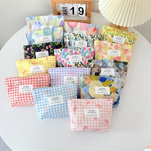 Various floral and plaid canvas makeup bags arranged on a table for visual variety