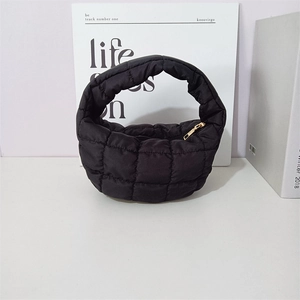 Macro detail of black quilted puff handbag featuring square stitching and metallic zipper