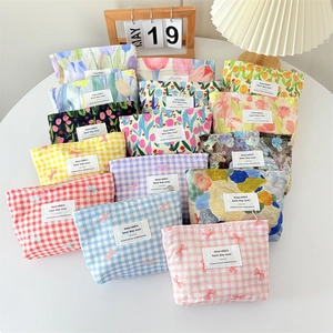 Flat lay of multiple floral and checkered canvas makeup bags in assorted colors on a table