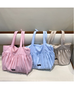 Close-up of pleated cotton linen tote bags in pink, blue, and beige with Romance labels