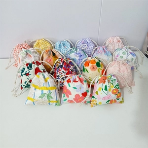 Detailed overhead view of multiple cotton drawstring pouches with floral and plaid prints