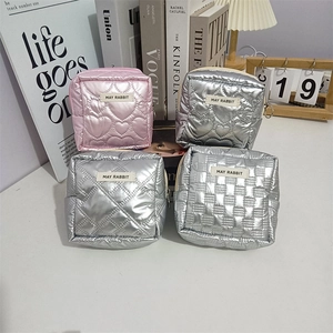 Quilted heart PU makeup bags in pink and silver set on a stylish white desk surface