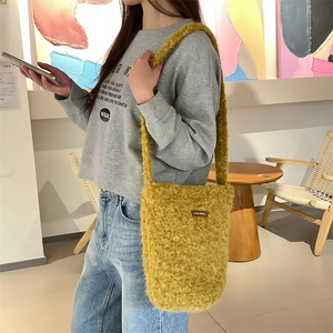 Détail d'un sac seau en peluche jaune gingembre avec étiquette et texture en fausse fourrure