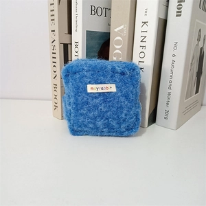 Detailaufnahme einer blauen Plüschtasche mit mayrabbit-Webetikett auf weißem Tisch