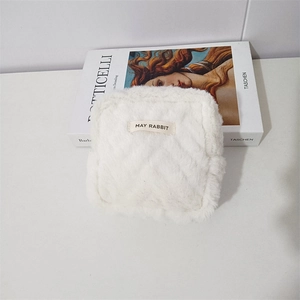 Detailed close-up of a white plush square pouch with diamond quilting and May Rabbit tag