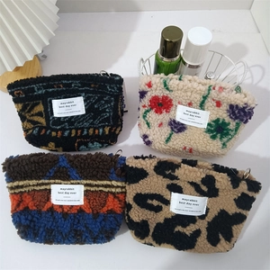 Set of four plush lamb wool cosmetic bags with various patterns in a cozy setting