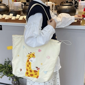 Détail de girafe brodée sur un grand sac cabas en toile crème pour femme