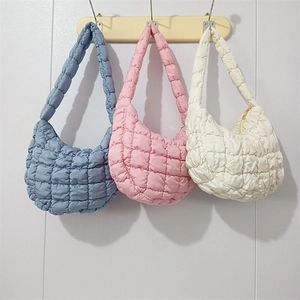 Three quilted puff cloud bags in blue, pink and white hanging on a wooden rack