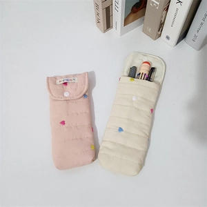 Detailed view of quilted cotton pouches showing colorful heart embroidery and snap closure