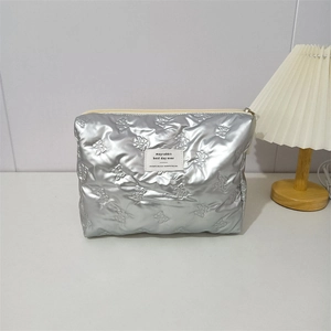 Macro detail of silver quilted PU makeup bag with embossed bow patterns and zip closure