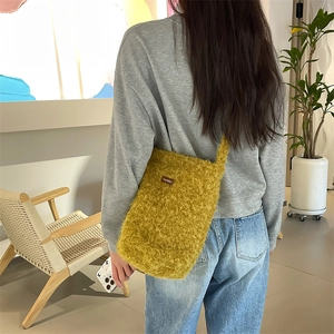 Détail du sac seau en peluche jaune porté à l'épaule avec une texture en fourrure douce