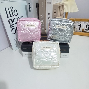 Detail of heart-quilted PU makeup pouches in pink, silver, and beige with metal rings