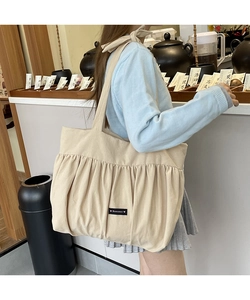 Detail of beige pleated canvas tote bag with romance tag showing thick texture and fabric