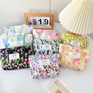 Detailed view of floral canvas makeup bags with zippers on a white circular table