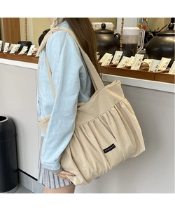 Close-up of beige cotton linen tote bag with pleated texture and Romance label detail
