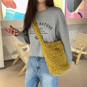 Détail d'un sac à bandoulière en peluche jaune moutarde montrant la texture et l'étiquette