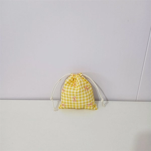 Detail of yellow checkered cotton drawstring bag with pink bow pattern and white cords