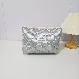 Macro detail of quilted silver makeup bag with square label and metal zipper closure