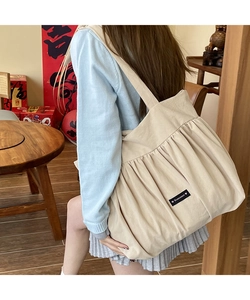 Detailed texture of beige canvas tote bag with romance patch and pleated design