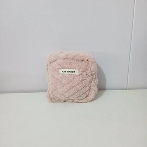 Close-up of pink plush square bag with a May Rabbit label and smooth metal zipper detail