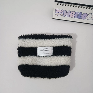 Close-up of black and white striped plush cosmetic bag with a branded cloth label